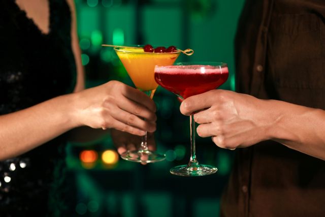 カクテルで乾杯する男女の手