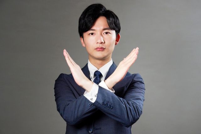 胸の前でバツサインをする男性